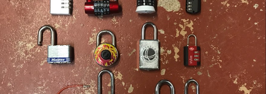Photograph of twelve different locks laid out on a rough cement floor